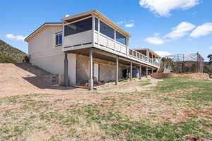 Rear view of property with a sunroom and a wooden deck