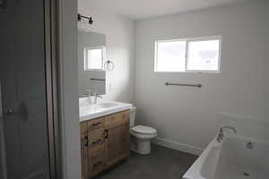 Bathroom featuring toilet, a bathtub, baseboards, and vanity