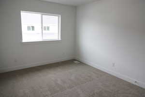 Spare room featuring carpet flooring, baseboards, and visible vents