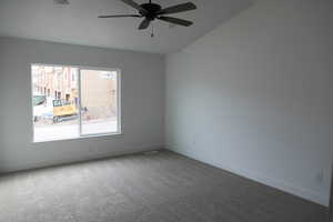 Empty room featuring ceiling fan, baseboards, carpet, and lofted ceiling
