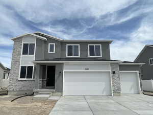 View of front facade featuring concrete driveway, a garage, stone siding, and stucco siding