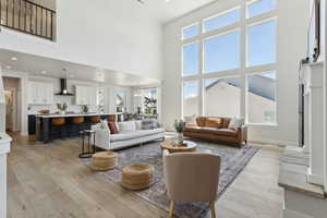 Living area featuring light wood-type flooring, a high ceiling, and a wealth of natural light