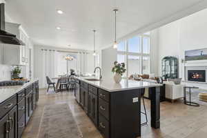Kitchen featuring a sink, wall chimney range hood, light countertops, appliances with stainless steel finishes, and a breakfast bar area