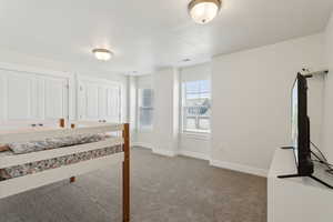 Unfurnished bedroom with a textured ceiling, carpet flooring, baseboards, and visible vents