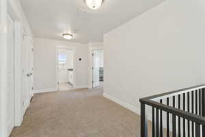 Corridor with light carpet, visible vents, and baseboards