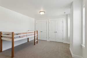 Unfurnished bedroom with carpet flooring, visible vents, baseboards, and two closets