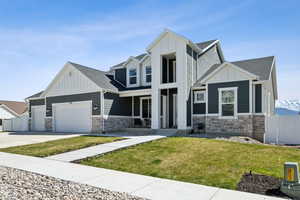 View of front of home featuring an attached garage, board and batten siding, fence, and stone siding