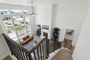 Staircase with baseboards, a warm lit fireplace, ceiling fan, recessed lighting, and a towering ceiling