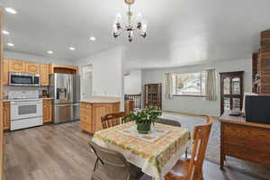 Dining room with light wood-type flooring, recessed lighting, and a notable chandelier