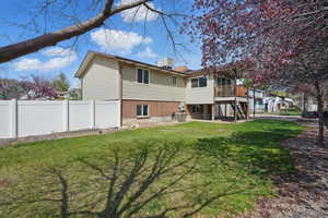 Rear view of property with stairs, a patio area, a deck, fence, and a lawn