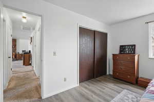 Bedroom featuring a closet, visible vents, light wood-type flooring, and baseboards