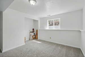 Carpeted empty room with visible vents and baseboards