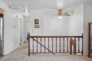 Hall with visible vents, light colored carpet, baseboards, and an upstairs landing