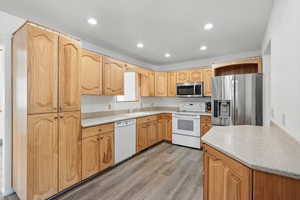 Kitchen with appliances with stainless steel finishes, light wood finished floors, a sink, and recessed lighting