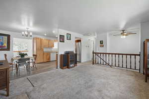 Living area featuring light wood-style floors, ceiling fan with notable chandelier, and recessed lighting