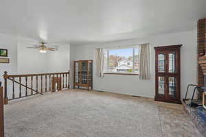Empty room featuring carpet, visible vents, baseboards, and ceiling fan