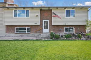 Rear view of property featuring brick siding, entry steps, and a lawn