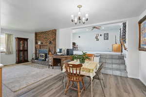 Dining room featuring baseboards, recessed lighting, a wood stove, ceiling fan with notable chandelier, and wood finished floors