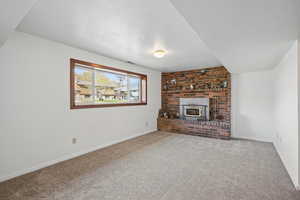 Unfurnished living room featuring visible vents, baseboards, a textured ceiling, and carpet floors