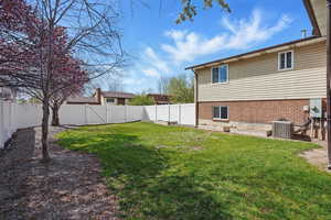 View of yard with central air condition unit and a fenced backyard