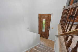 Entrance foyer with stairway, baseboards, and light tile patterned flooring
