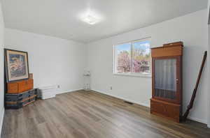 Empty room featuring visible vents, baseboards, and wood finished floors