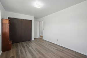Unfurnished bedroom with a closet, baseboards, and wood finished floors