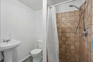 Full bath featuring a sink, baseboards, a tile shower, and toilet