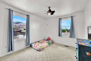 Bedroom featuring carpet, a textured ceiling, baseboards, and a ceiling fan