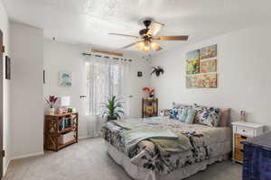 Bedroom with light carpet, a textured ceiling, baseboards, and ceiling fan