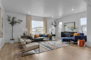 Living area with baseboards, recessed lighting, and light wood-style floors