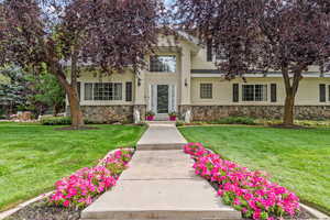 View of front of house featuring a front yard, stucco siding, stone siding, and a chimney.