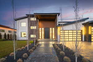 Contemporary home featuring stone siding, a front yard, and stucco siding
