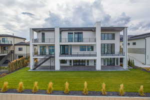 Back of property with a lawn, stairway, stucco siding, and a patio area
