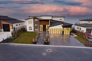 Contemporary house featuring driveway, an attached garage, stucco siding, a yard, and stone siding