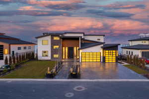 Contemporary house featuring stone siding, driveway, an attached garage, and stucco siding