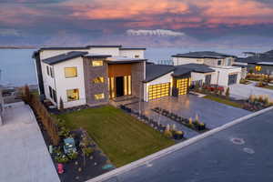 Contemporary home featuring a front lawn, driveway, stone siding, and stucco siding