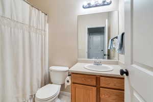 Full bath featuring a shower with shower curtain, vanity, and toilet