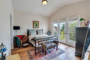 Bedroom featuring access to outside, lofted ceiling, and light wood-type flooring