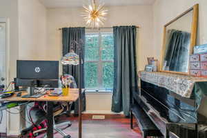 Home office with a chandelier, visible vents, baseboards, and wood finished floors
