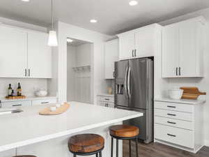 Kitchen featuring a kitchen breakfast bar, recessed lighting, light stone counters, dark wood-style flooring, and stainless steel fridge