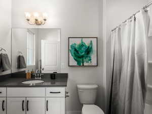 Full bath with toilet, vanity, and a shower with curtain