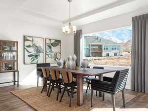 Dining room featuring a tray ceiling, an inviting chandelier, and wood finished floors