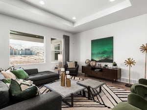 Living room with visible vents, recessed lighting, wood finished floors, a raised ceiling, and baseboards