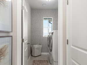 Laundry room featuring independent washer and dryer, visible vents, laundry area, and light tile patterned flooring