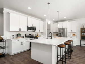 Kitchen with a kitchen breakfast bar, a sink, dark wood-style floors, and stainless steel appliances