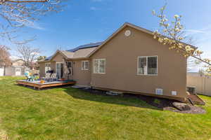 Back of property with a lawn, fence, an outdoor structure, a storage unit, and a wooden deck