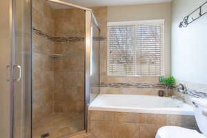 Bathroom with a shower stall, a bath, and toilet