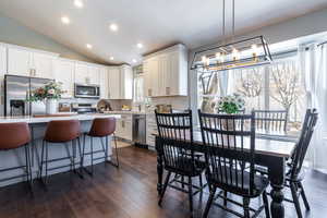 Kitchen featuring tasteful backsplash, vaulted ceiling, appliances with stainless steel finishes, light countertops, and a notable chandelier