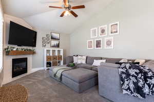 Living room featuring a tile fireplace, high vaulted ceiling, a ceiling fan, and carpet